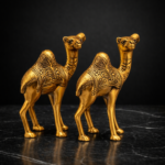 handicraft golden metal rajasthani 5 inch camel showpiece pair living room decorations 2 psc this pair of golden camel figurines beautifully captures traditional charm with a touch of elegance. crafted with intricate hand etched patterns, each camel showcases detailed floral and geometric designs that reflect classic artisanal craftsmanship. the rich gold finish adds warmth and a regal feel, making these figurines perfect for enhancing shelves, console tables, or office desks. symbolizing endurance, prosperity, and journey, camel décor pieces are often associated with positivity and strength. ideal for: living room or hallway décor office desk or bookshelf festive styling or thoughtful gifting